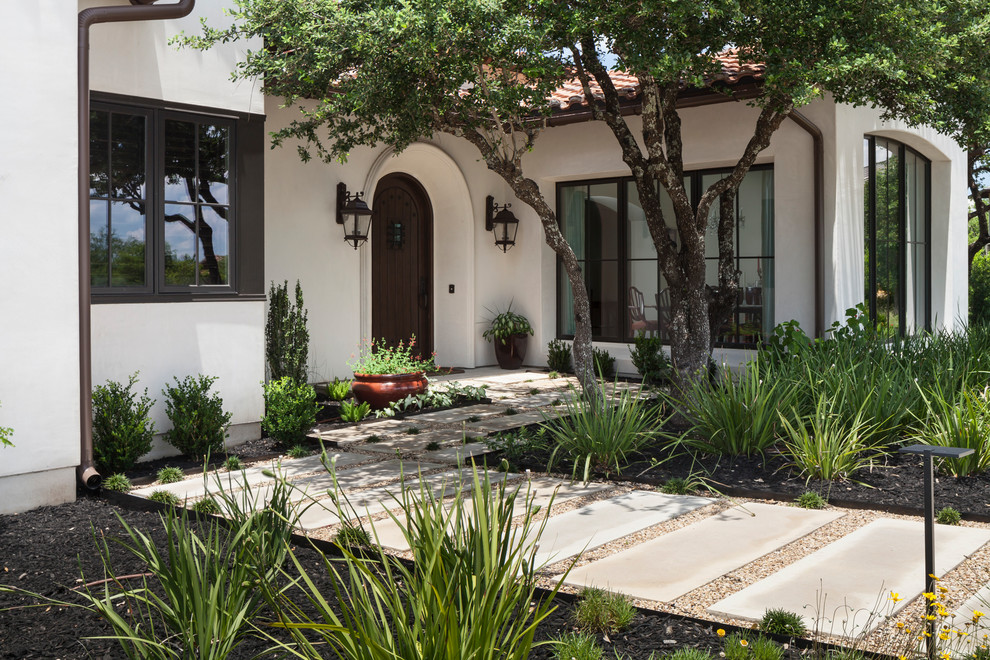 Photo of a white house exterior in Austin with stone veneer and a tile roof.