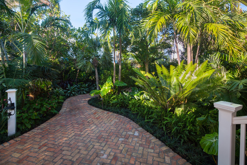 Design ideas for a mid-sized tropical front yard partial sun garden in Miami with brick pavers.