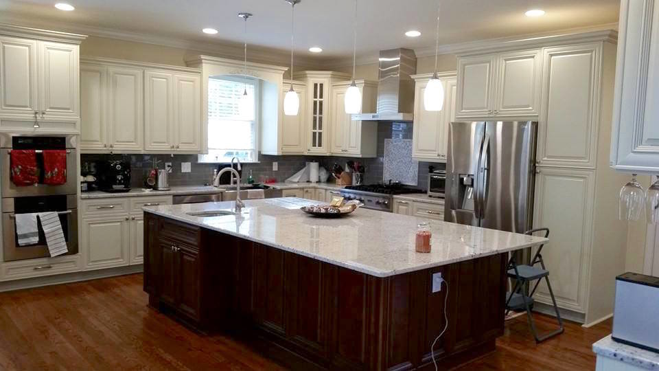 Large transitional l-shaped dark wood floor and brown floor eat-in kitchen photo in Miami with a farmhouse sink, raised-panel cabinets, white cabinets, gray backsplash, subway tile backsplash, stainless steel appliances and an island