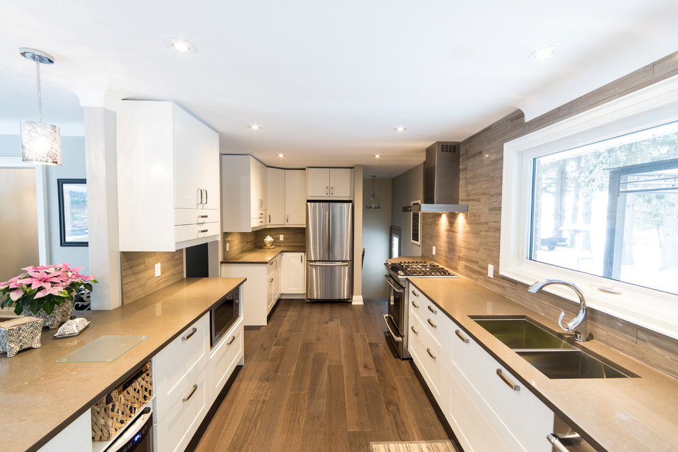 Design ideas for a mid-sized transitional galley eat-in kitchen in Toronto with an undermount sink, recessed-panel cabinets, white cabinets, quartz benchtops, brown splashback, porcelain splashback, stainless steel appliances, porcelain floors, a peninsula, brown floor and grey benchtop.