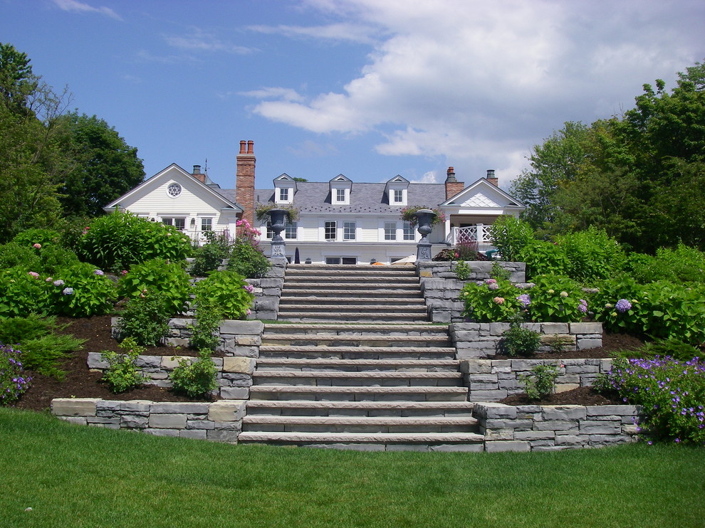 Expansive traditional sloped garden in New York with natural stone pavers for summer.