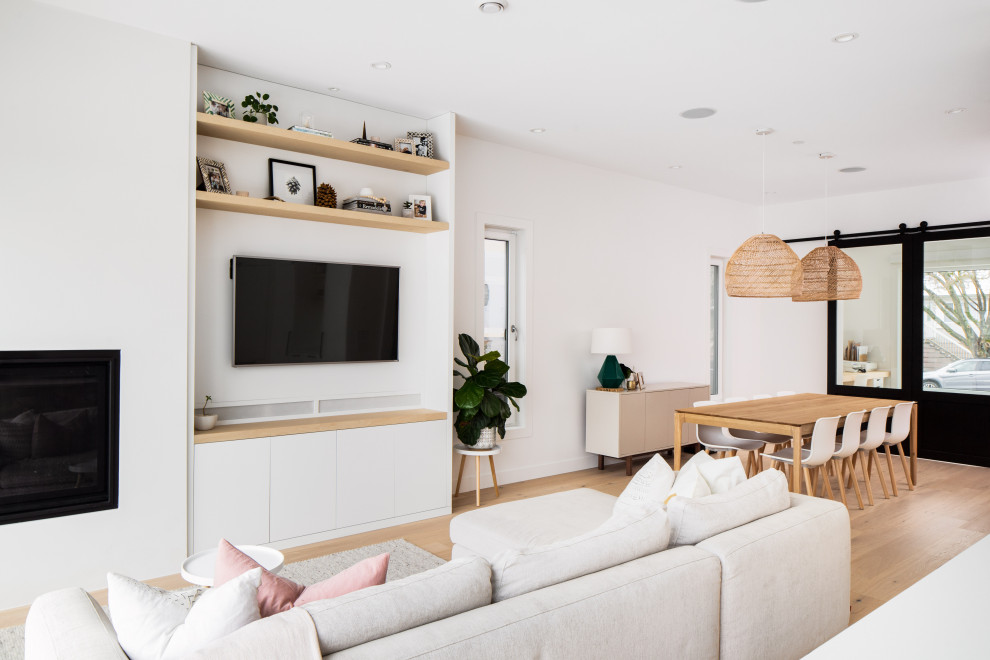 Geräumiges Skandinavisches Wohnzimmer im Loft-Stil mit weißer Wandfarbe, Laminat, Gaskamin, Kaminumrandung aus Beton, TV-Wand und beigem Boden in Vancouver