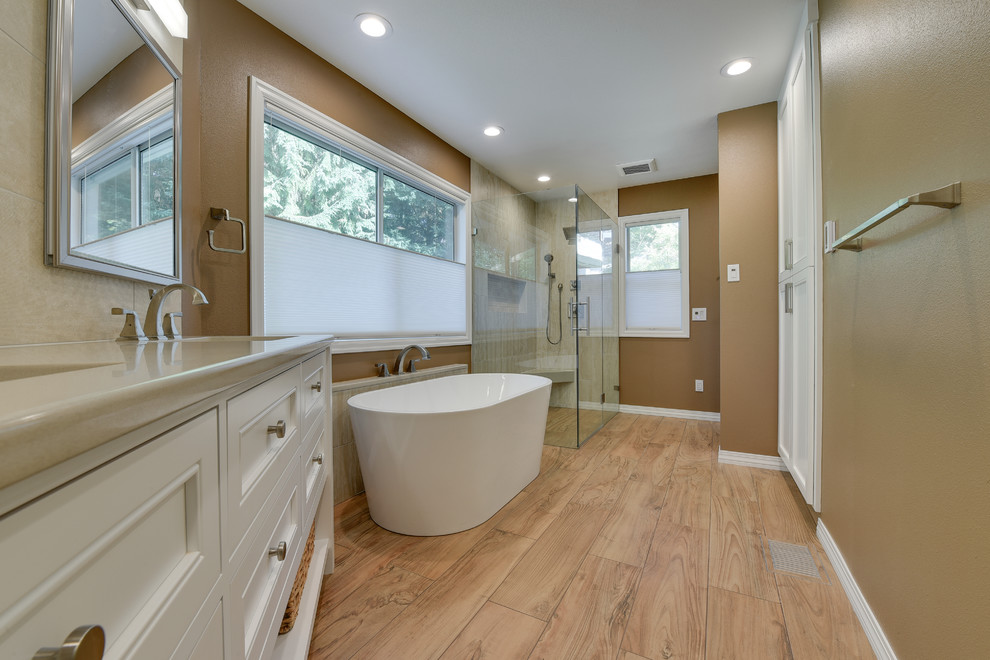 Photo of a large transitional master bathroom in Portland with recessed-panel cabinets, beige cabinets, a freestanding tub, a curbless shower, beige tile, porcelain tile, brown walls, porcelain floors, an undermount sink, engineered quartz benchtops, brown floor and a hinged shower door.