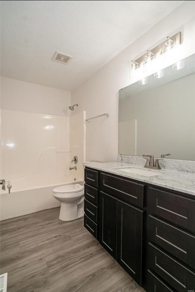 Cette image montre une grande salle de bain principale minimaliste avec un placard à porte shaker, des portes de placard noires, une baignoire en alcôve, un espace douche bain, un mur blanc, un sol en vinyl, un lavabo encastré, un plan de toilette en quartz modifié, un sol gris, une cabine de douche avec un rideau, un plan de toilette gris, meuble simple vasque et meuble-lavabo encastré.