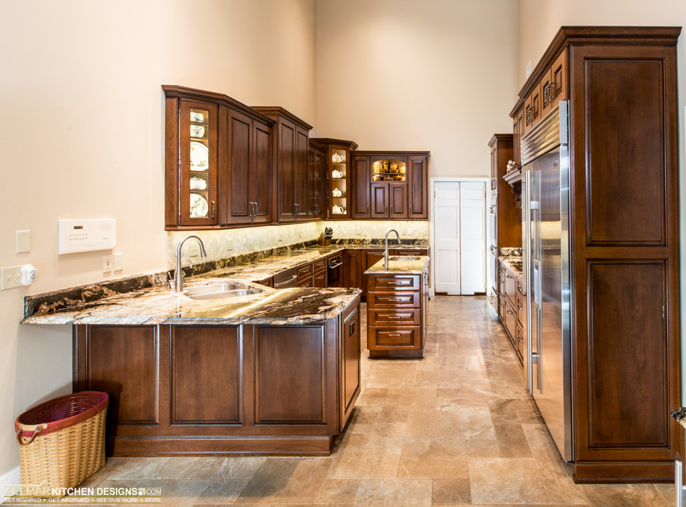 This is an example of a large traditional u-shaped eat-in kitchen in Orlando with an undermount sink, raised-panel cabinets, medium wood cabinets, granite benchtops, beige splashback, stone tile splashback, travertine floors and with island.