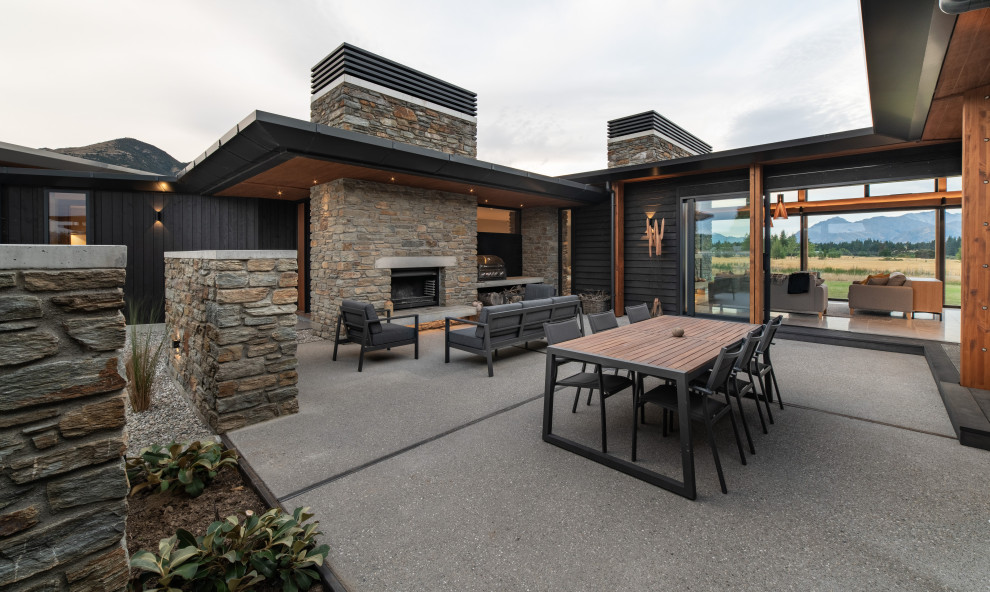 Photo of a large modern courtyard patio in Other with with fireplace and concrete slab.