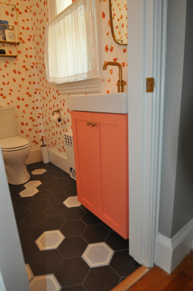 This is an example of a small transitional bathroom in Boston with shaker cabinets, orange cabinets, a two-piece toilet, porcelain floors, an integrated sink, black floor, white benchtops, a single vanity, a built-in vanity and wallpaper.