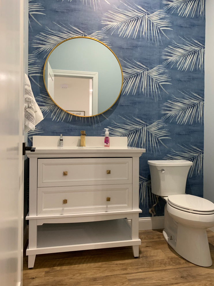 This is an example of a large traditional shower room bathroom in Other with recessed-panel cabinets, white cabinets, a one-piece toilet, blue walls, vinyl flooring, a submerged sink, engineered stone worktops, brown floors, white worktops, a single sink, a built in vanity unit and wallpapered walls.