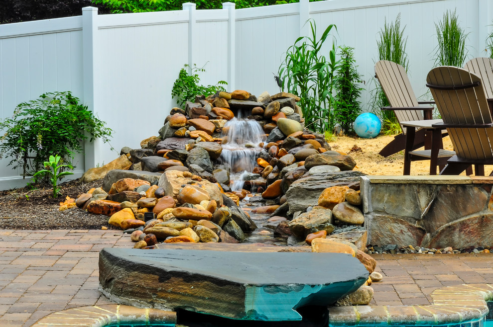 Pool fountain - rustic backyard stone and rectangular lap pool fountain idea in Baltimore