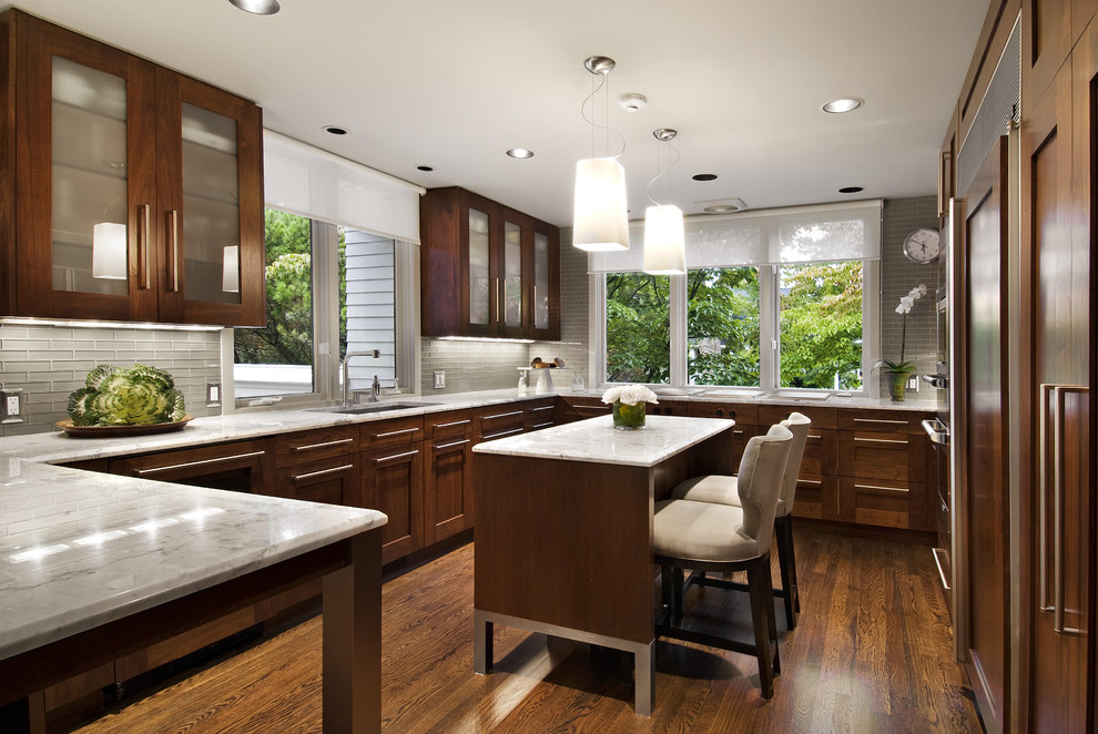 Mid-sized contemporary u-shaped separate kitchen in Detroit with glass-front cabinets, panelled appliances, an undermount sink, marble benchtops, grey splashback, glass tile splashback, with island, dark wood cabinets and dark hardwood floors.