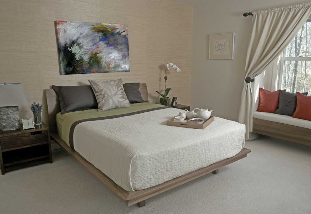 This is an example of a contemporary master bedroom in New York with beige walls and carpet.