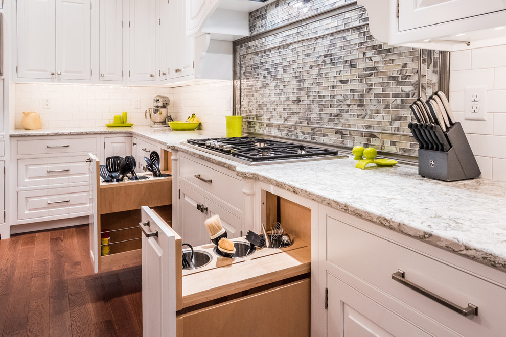 Example of a large transitional galley medium tone wood floor eat-in kitchen design with a farmhouse sink, beaded inset cabinets, white cabinets, granite countertops, white backsplash, mosaic tile backsplash, stainless steel appliances and an island