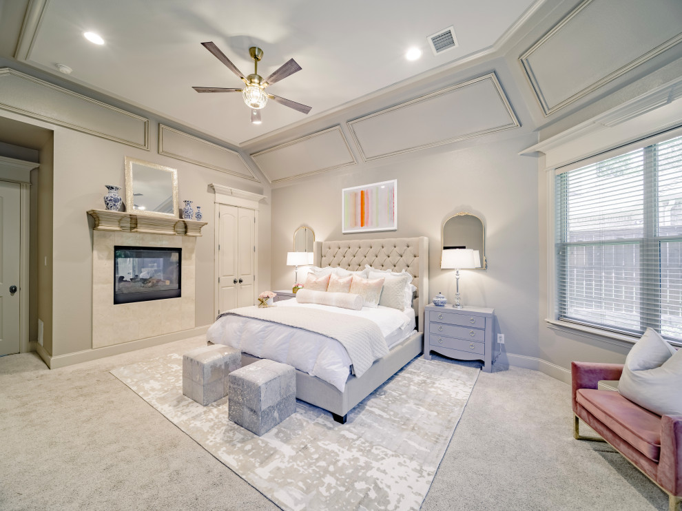 На фото: большая хозяйская спальня в классическом стиле с бежевыми стенами, ковровым покрытием, двусторонним камином, фасадом камина из плитки, бежевым полом и кессонным потолком