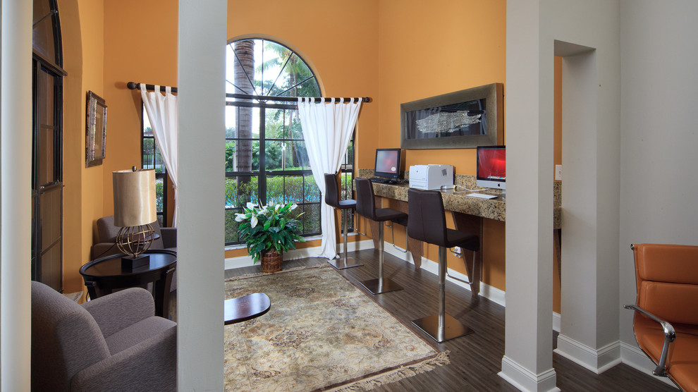 This is an example of a mid-sized transitional study room in Miami with orange walls, laminate floors and a built-in desk.