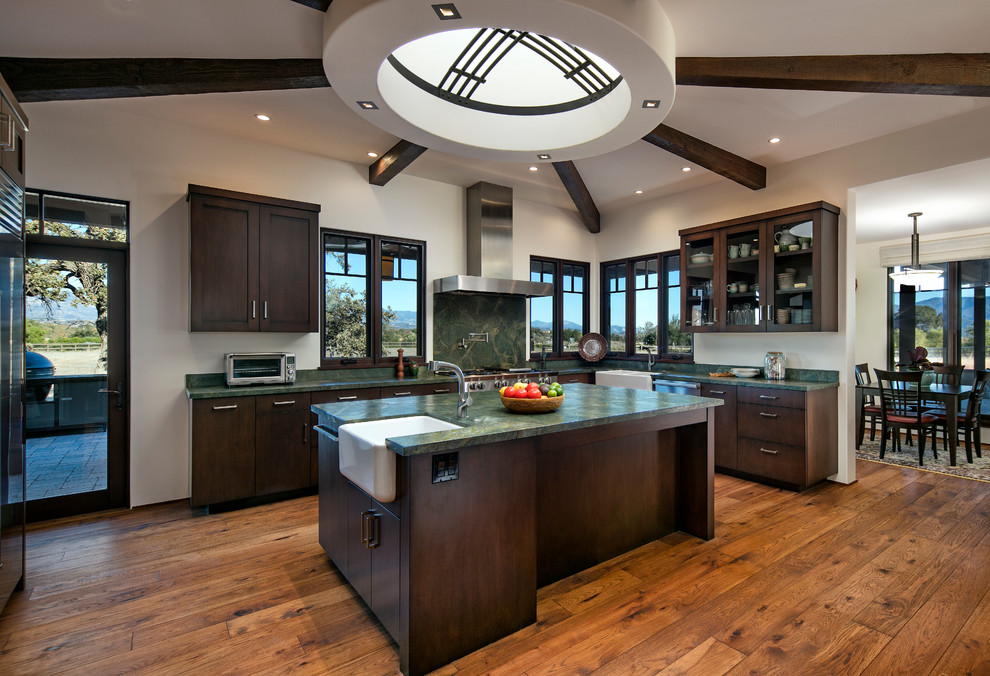 Design ideas for a large transitional separate kitchen in San Luis Obispo with a farmhouse sink, glass-front cabinets, dark wood cabinets, marble benchtops, green splashback, marble splashback, stainless steel appliances, with island, medium hardwood floors and orange floor.