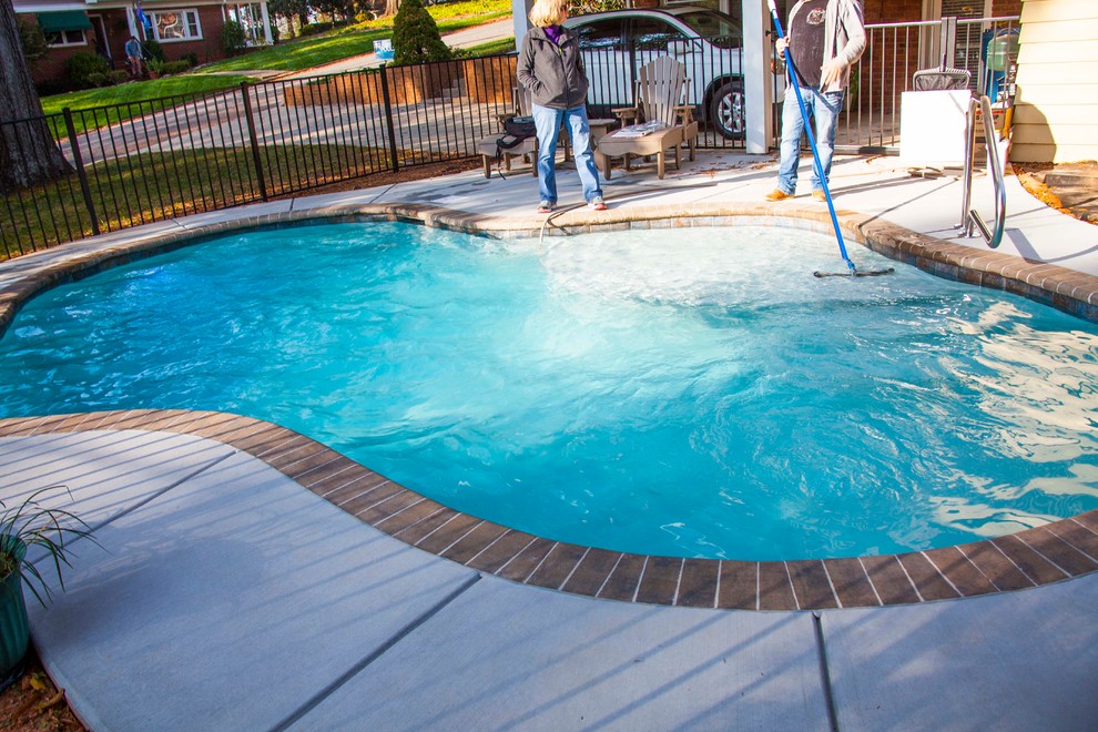 This is an example of a small arts and crafts backyard custom-shaped natural pool in Charlotte with decking.