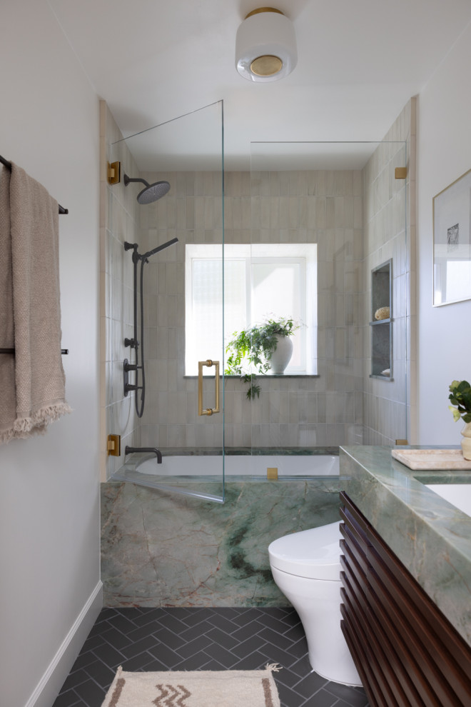 Стильный дизайн: маленькая ванная комната в современном стиле с темными деревянными фасадами, полновстраиваемой ванной, душем над ванной, раздельным унитазом, бежевой плиткой, керамической плиткой, белыми стенами, полом из керамической плитки, врезной раковиной, столешницей из гранита, черным полом, душем с распашными дверями, зеленой столешницей, тумбой под одну раковину и напольной тумбой для на участке и в саду - последний тренд
