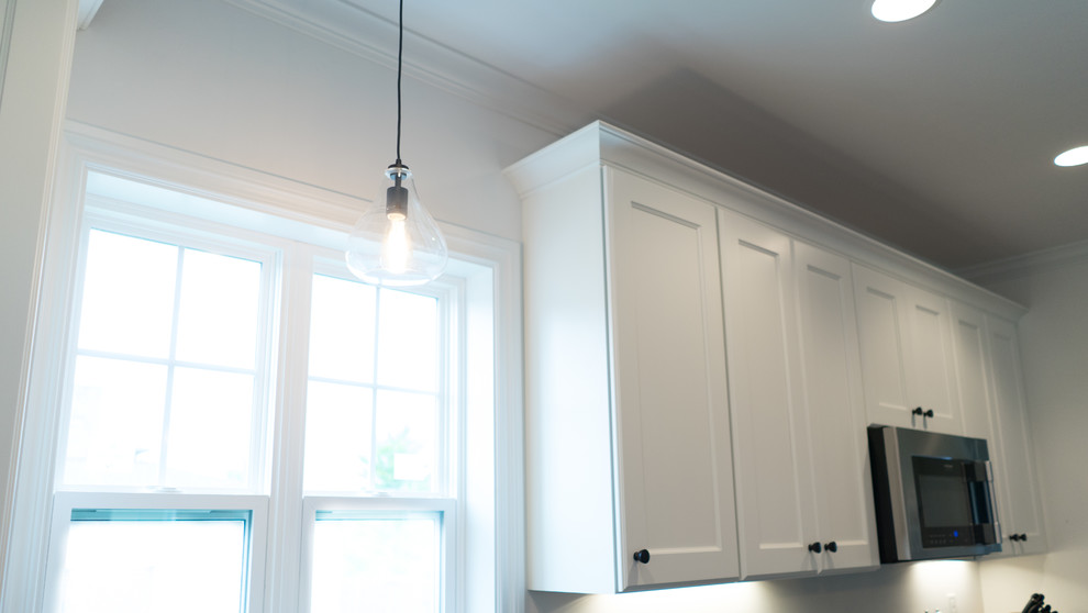 Mid-sized transitional l-shaped dark wood floor open concept kitchen photo with an undermount sink, shaker cabinets, white cabinets, granite countertops, gray backsplash, stainless steel appliances and an island