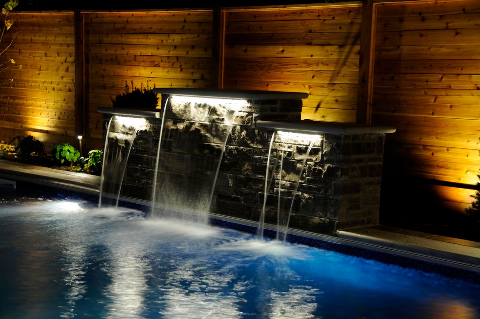Large transitional backyard stone and rectangular lap pool fountain photo in Toronto