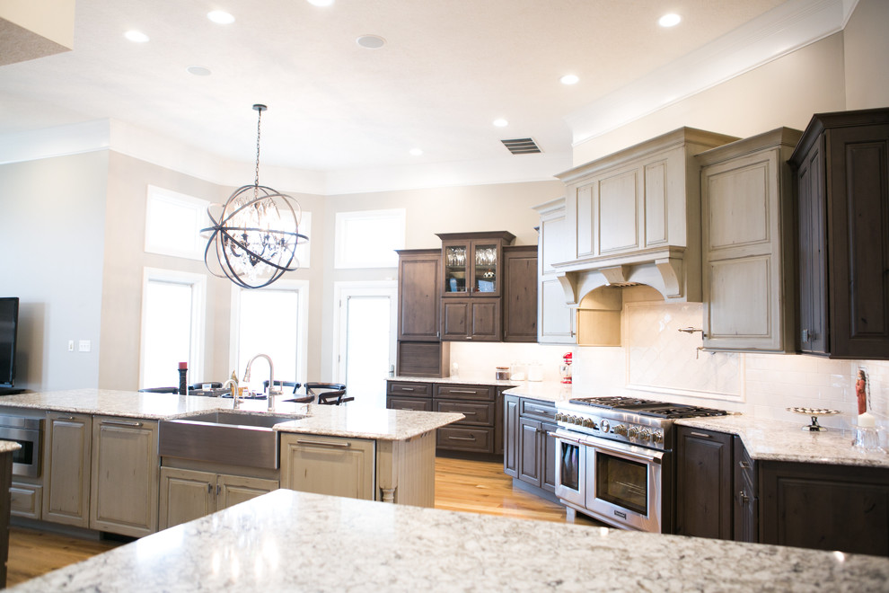 Inspiration for a large transitional u-shaped medium tone wood floor and brown floor kitchen remodel in Indianapolis with a farmhouse sink, raised-panel cabinets, dark wood cabinets, granite countertops, white backsplash, subway tile backsplash, paneled appliances, an island and multicolored countertops