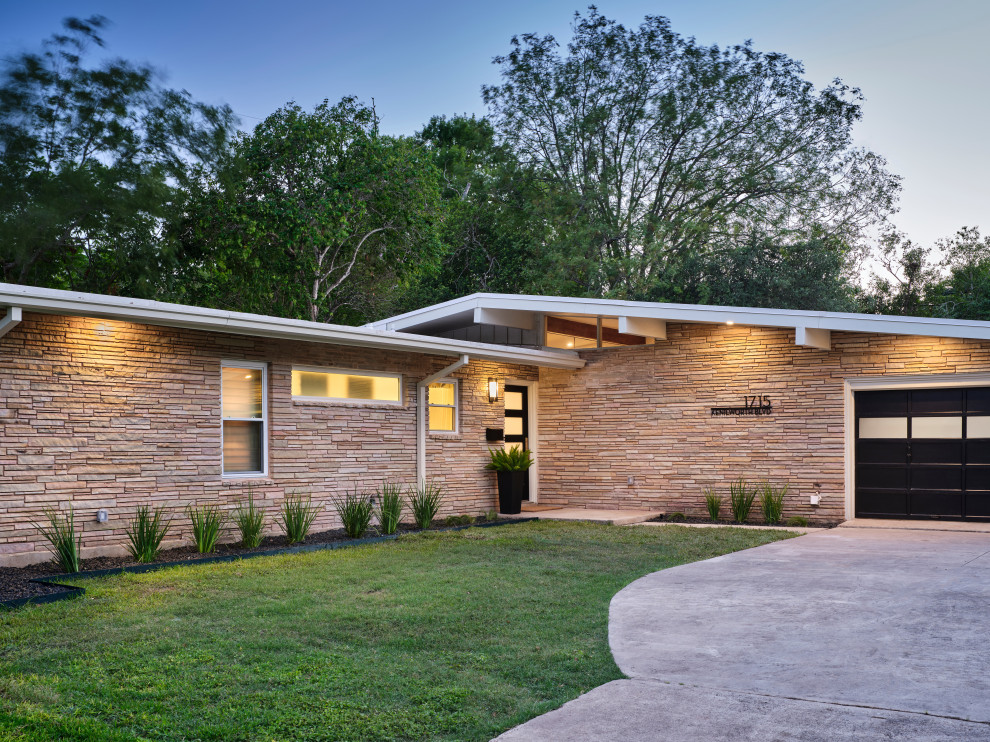 Mid-sized mid-century modern beige one-story stone exterior home idea in Austin with a mixed material roof and a black roof