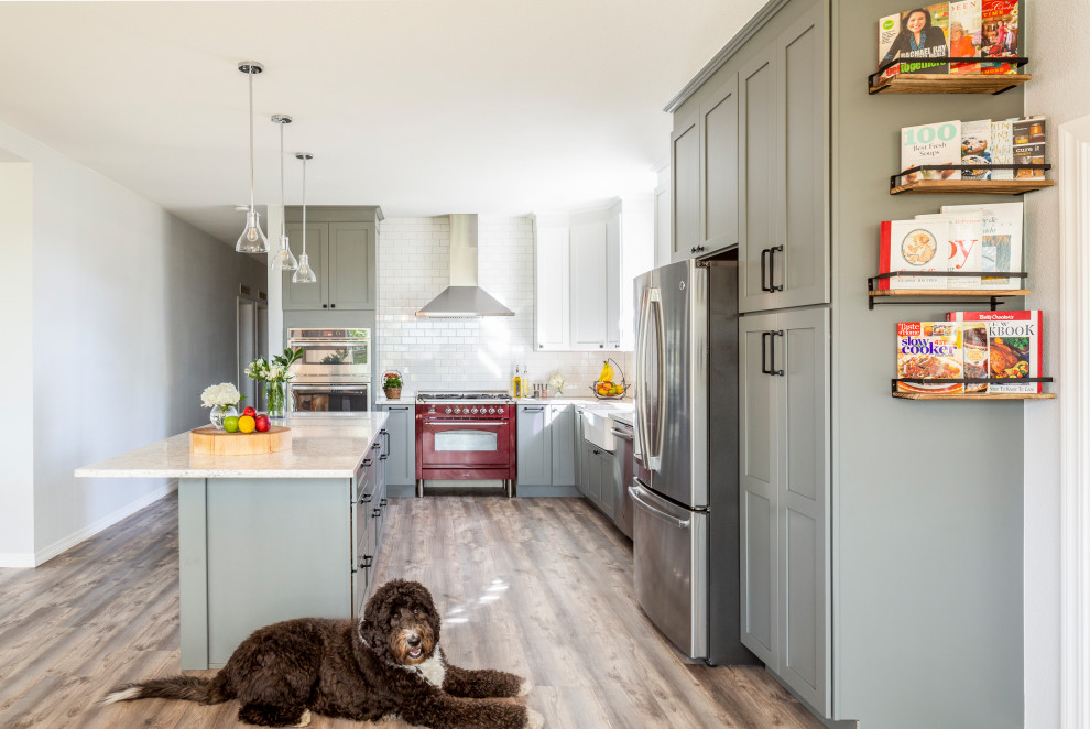 Design ideas for a large transitional l-shaped eat-in kitchen in Denver with a farmhouse sink, shaker cabinets, grey cabinets, white splashback, with island, brown floor, white benchtop, quartz benchtops, ceramic splashback, stainless steel appliances and light hardwood floors.