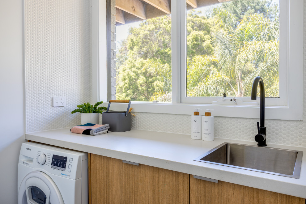 Inspiration for a small scandinavian galley dedicated laundry room in Melbourne with a drop-in sink, open cabinets, light wood cabinets, quartz benchtops, white walls, medium hardwood floors, a side-by-side washer and dryer and white benchtop.