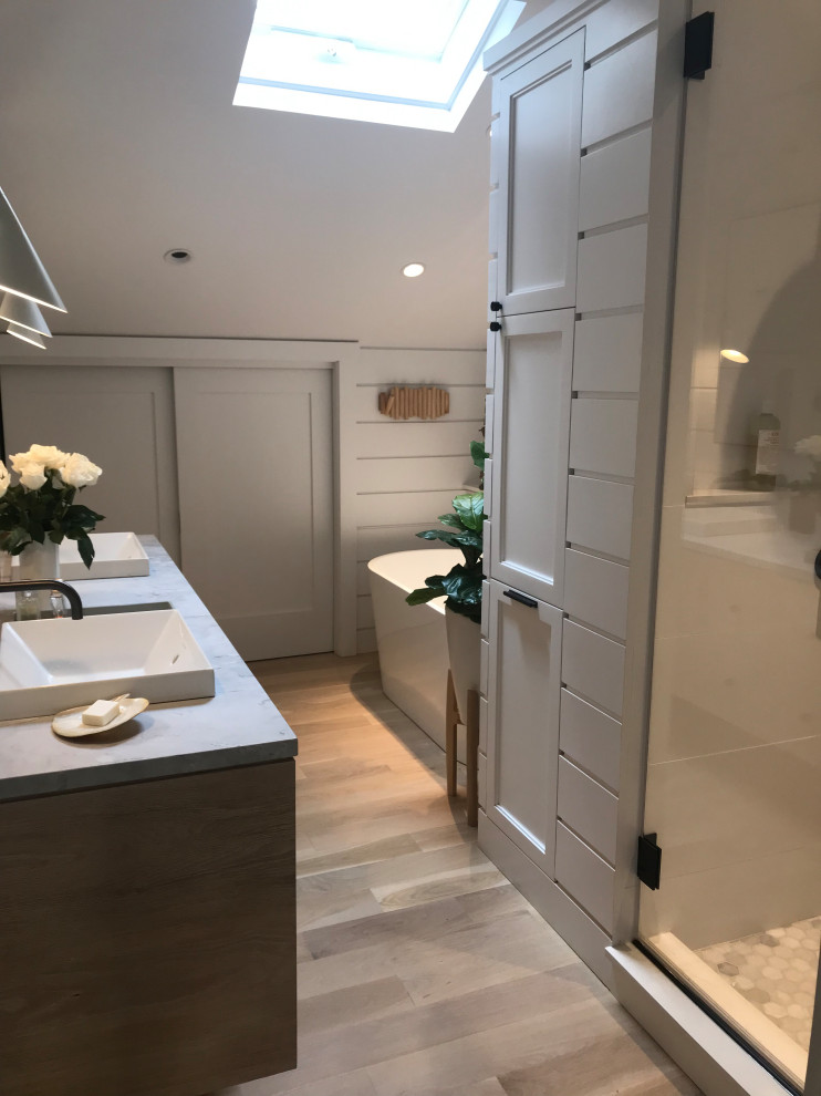 Inredning av ett nordiskt litet grå grått en-suite badrum, med släta luckor, skåp i ljust trä, en öppen dusch, en vägghängd toalettstol, vita väggar, ett nedsänkt handfat, marmorbänkskiva och dusch med gångjärnsdörr