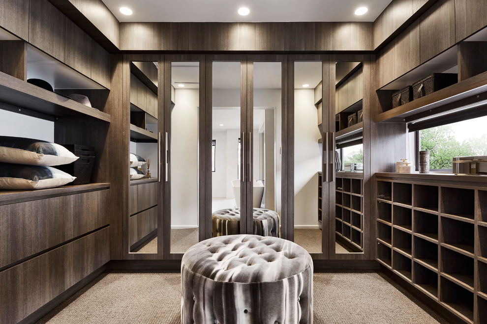 Photo of a contemporary gender-neutral dressing room in Sydney with flat-panel cabinets, dark wood cabinets, carpet and beige floor.