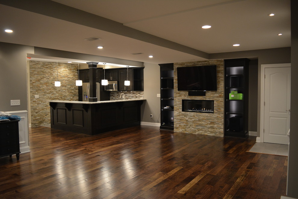 This is an example of a large transitional fully buried basement in Philadelphia with grey walls, dark hardwood floors and brown floor.