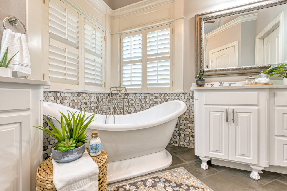 Mid-sized transitional master beige tile and porcelain tile porcelain tile and gray floor freestanding bathtub photo with raised-panel cabinets, white cabinets, a one-piece toilet, beige walls, an undermount sink, quartzite countertops, a hinged shower door and white countertops