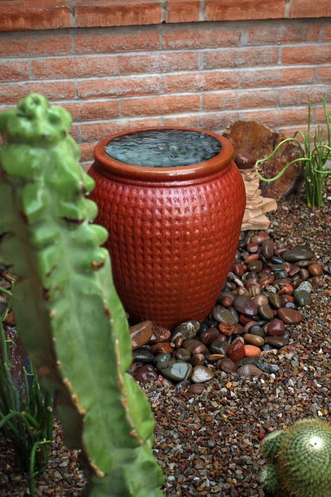 This is an example of a mid-sized front yard full sun xeriscape in Phoenix with brick pavers and a water feature.