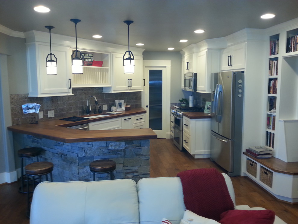 Example of a mid-sized transitional single-wall dark wood floor and brown floor enclosed kitchen design with an undermount sink, recessed-panel cabinets, white cabinets, wood countertops, gray backsplash, subway tile backsplash, stainless steel appliances and a peninsula