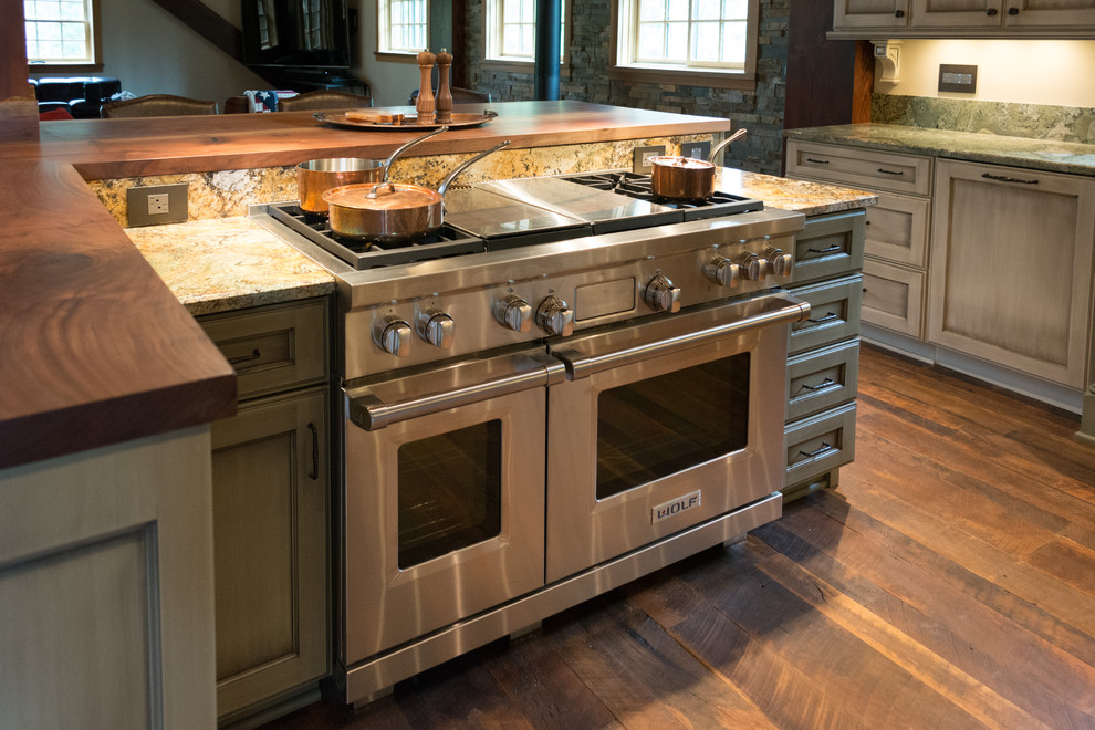 Open concept kitchen - large rustic l-shaped dark wood floor open concept kitchen idea in Portland with a farmhouse sink, recessed-panel cabinets, distressed cabinets, granite countertops, stone slab backsplash, stainless steel appliances and an island