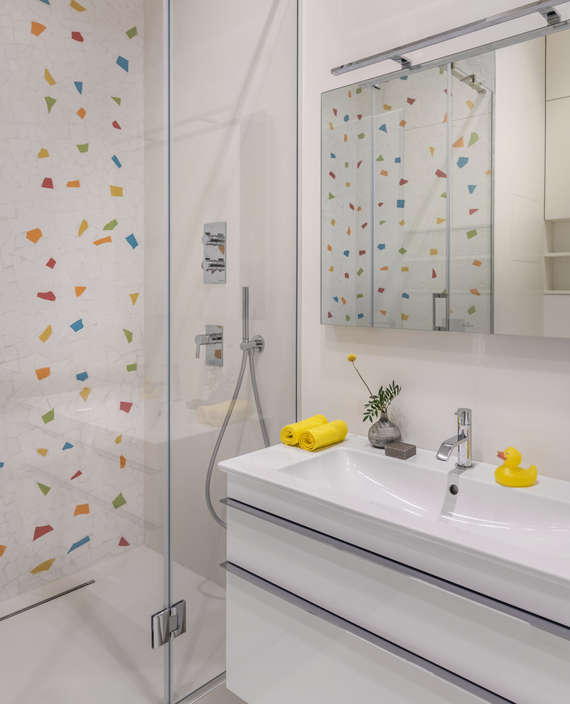 Inspiration for a small contemporary kids bathroom in Moscow with flat-panel cabinets, white cabinets, multi-coloured tile, white tile, a hinged shower door, an alcove shower, white walls, a console sink and white floor.