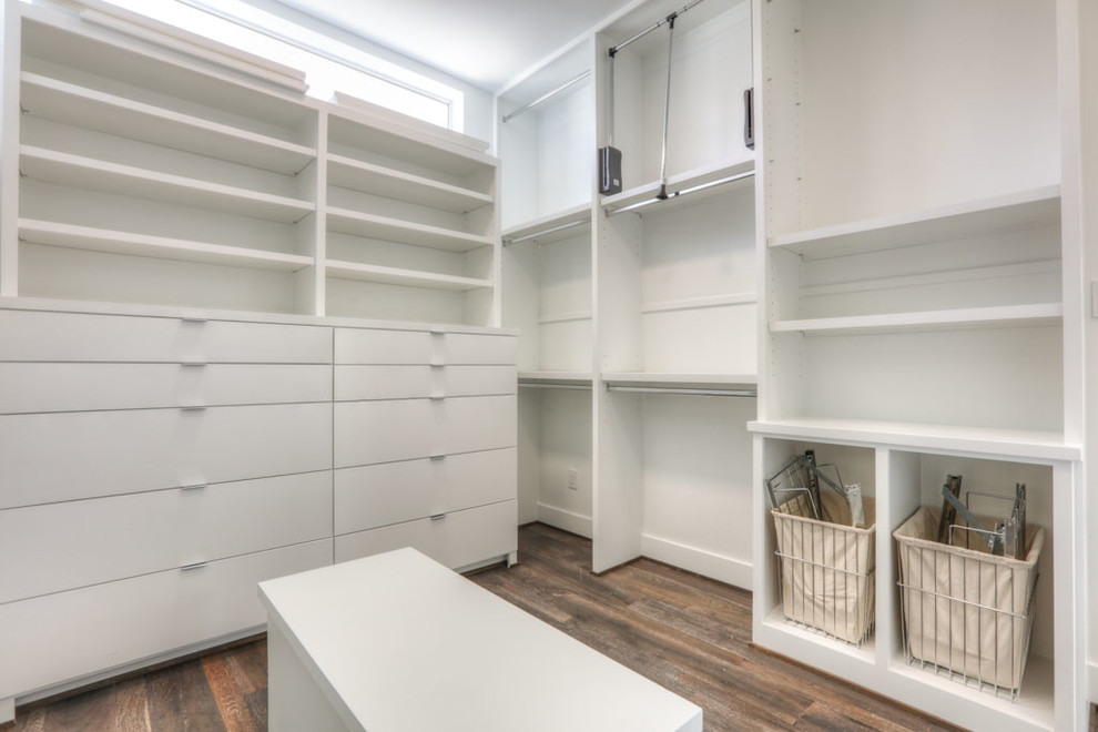 This is an example of a mid-sized modern gender-neutral walk-in wardrobe in Houston with open cabinets, white cabinets and beige floor.
