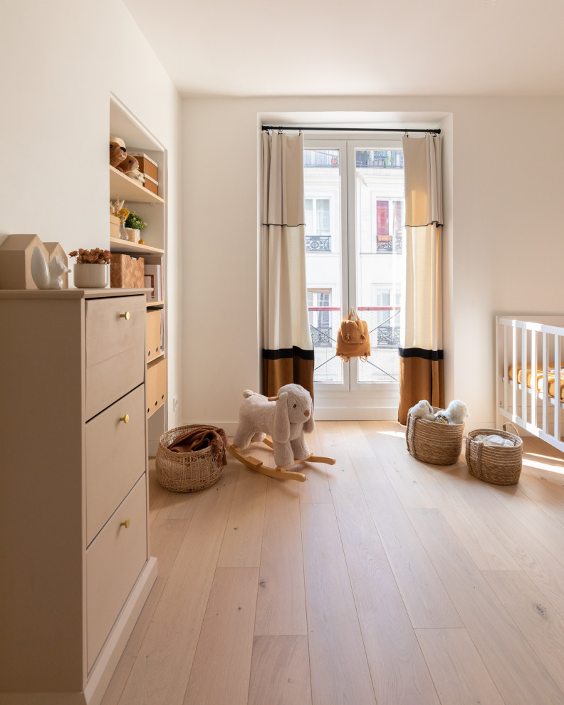 Diseño de habitación de bebé neutra tradicional de tamaño medio con paredes blancas y suelo beige