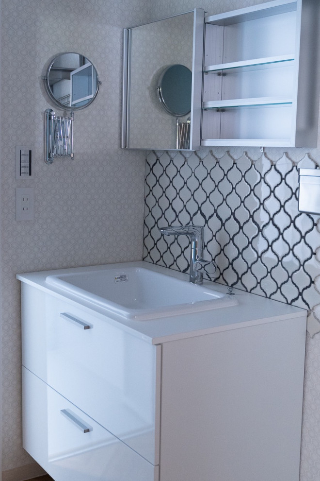 Photo of a small industrial powder room in Tokyo with beaded inset cabinets, white cabinets, white tile, mosaic tile, blue walls, vinyl floors, an undermount sink, laminate benchtops, beige floor, white benchtops, a freestanding vanity, wallpaper and wallpaper.