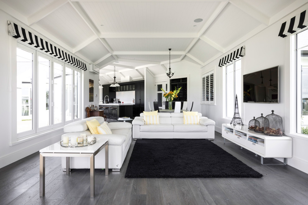 This is an example of a mid-sized transitional formal open concept living room in Auckland with dark hardwood floors, grey floor, white walls, a wall-mounted tv and no fireplace.