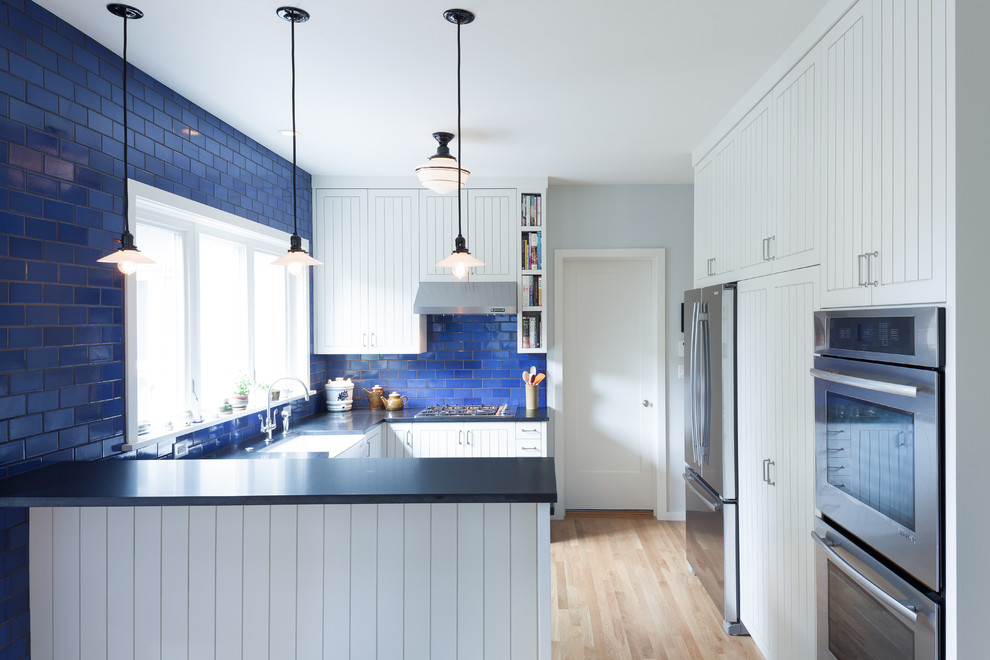 Contemporary u-shaped eat-in kitchen in Portland with stainless steel appliances, ceramic splashback, a farmhouse sink, granite benchtops, blue splashback, white cabinets and recessed-panel cabinets.