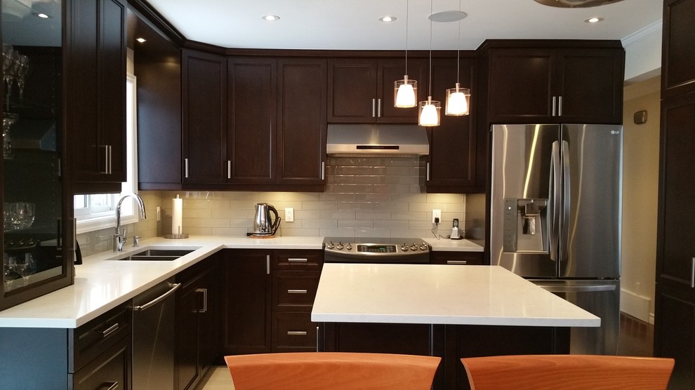 Photo of a mid-sized contemporary l-shaped eat-in kitchen in Montreal with a double-bowl sink, shaker cabinets, dark wood cabinets, granite benchtops, porcelain splashback, stainless steel appliances, porcelain floors and with island.