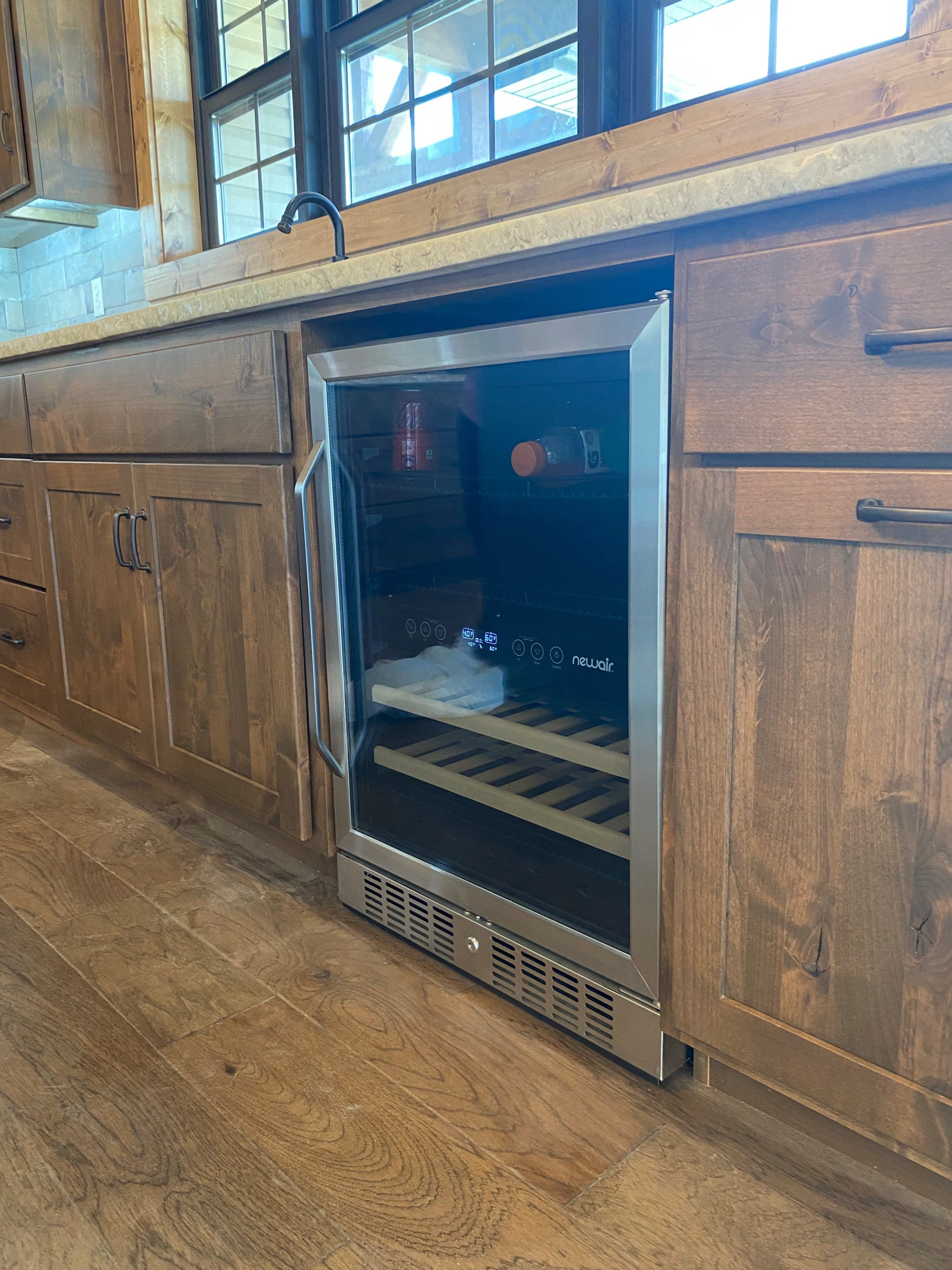 Wine cooler inside custom stained kitchen cabinetry