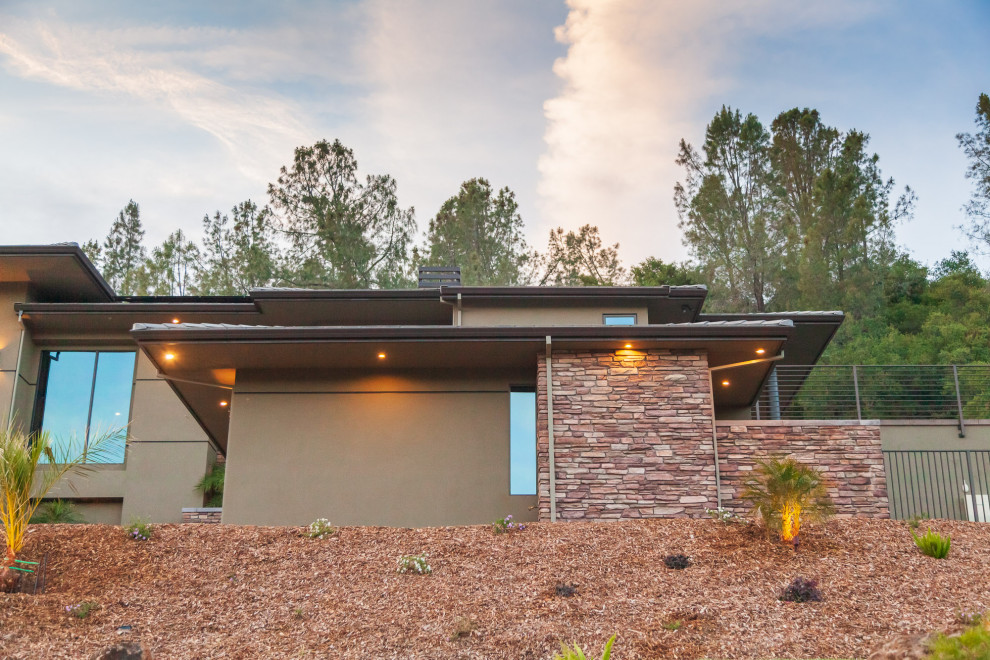Example of a large green split-level stucco house exterior design with a hip roof and a tile roof