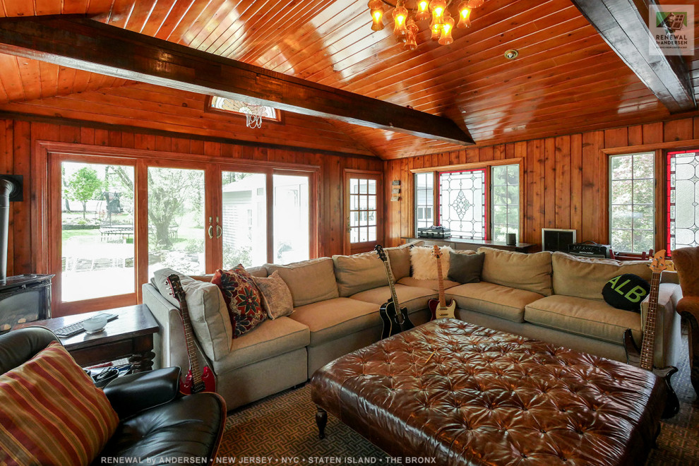 Cette image montre une grande salle de séjour en bois fermée avec une salle de musique, un mur marron, un téléviseur indépendant, un sol marron et un plafond en lambris de bois.