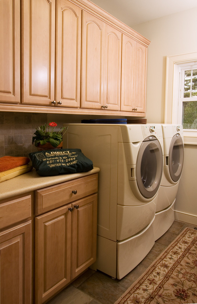 Inspiration for a small traditional single-wall laundry room in New York with raised-panel cabinets, light wood cabinets, laminate benchtops, white walls, slate floors and a side-by-side washer and dryer.