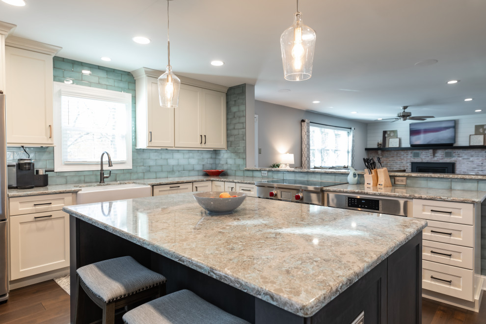 Mid-sized traditional l-shaped open plan kitchen in Philadelphia with a farmhouse sink, shaker cabinets, white cabinets, quartzite benchtops, blue splashback, porcelain splashback, stainless steel appliances, medium hardwood floors, with island, brown floor and beige benchtop.