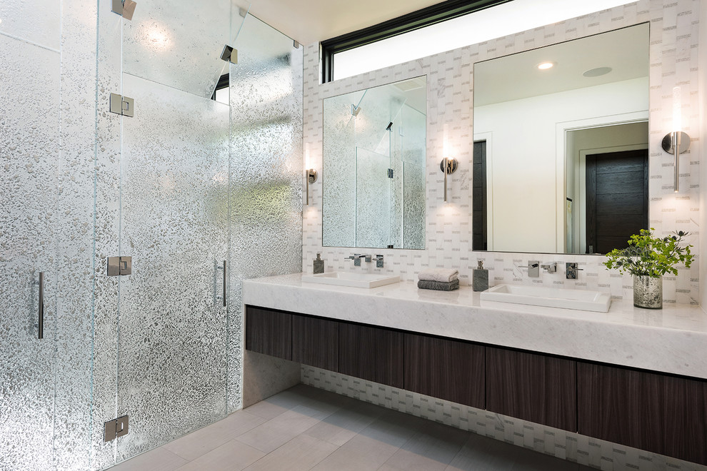 Contemporary master bathroom in San Diego with flat-panel cabinets, gray tile, multi-coloured tile, white tile, porcelain floors, a vessel sink, marble benchtops, grey floor, a hinged shower door, white benchtops, dark wood cabinets and a curbless shower.