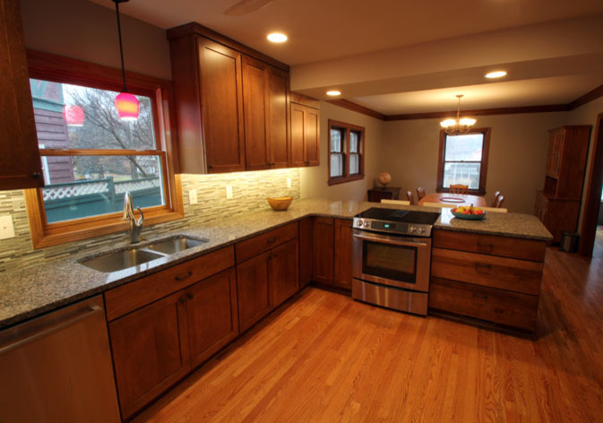 Large transitional single-wall light wood floor eat-in kitchen photo with an undermount sink, shaker cabinets, dark wood cabinets, granite countertops, multicolored backsplash, mosaic tile backsplash, stainless steel appliances and a peninsula
