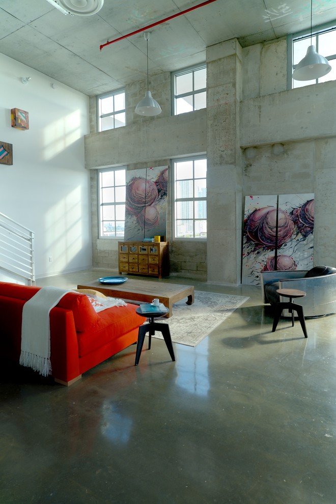 Large industrial open concept living room in Miami with white walls and concrete floors.