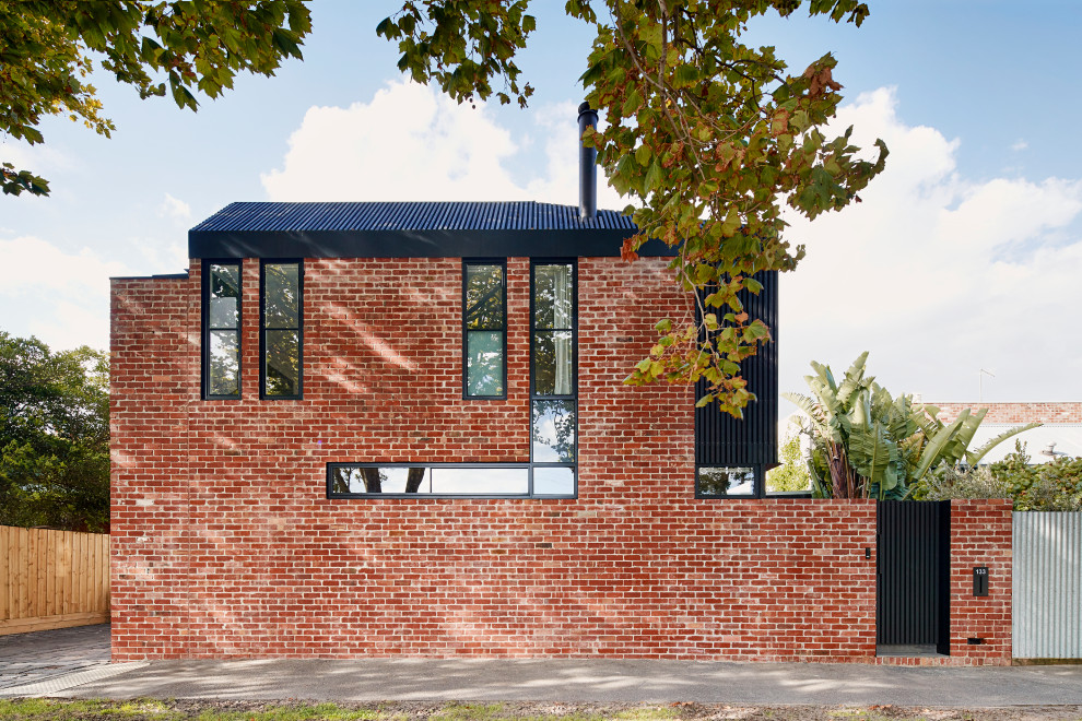 Diseño de fachada de casa roja industrial de dos plantas con revestimiento de ladrillo y tejado de metal